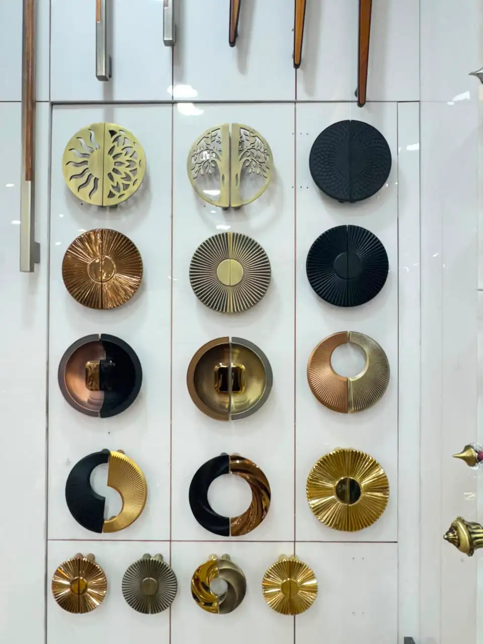 Display wall of designer round cabinet handles in brass, black and copper finishes