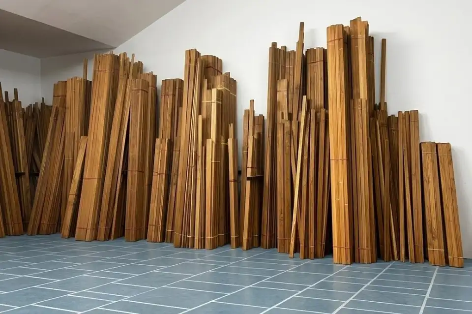 Bundles of seasoned teak planks stored upright on a tiled floor